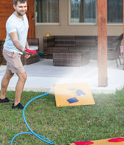 Man playing cornhole with Arctic Air® Personal Mister misting the area